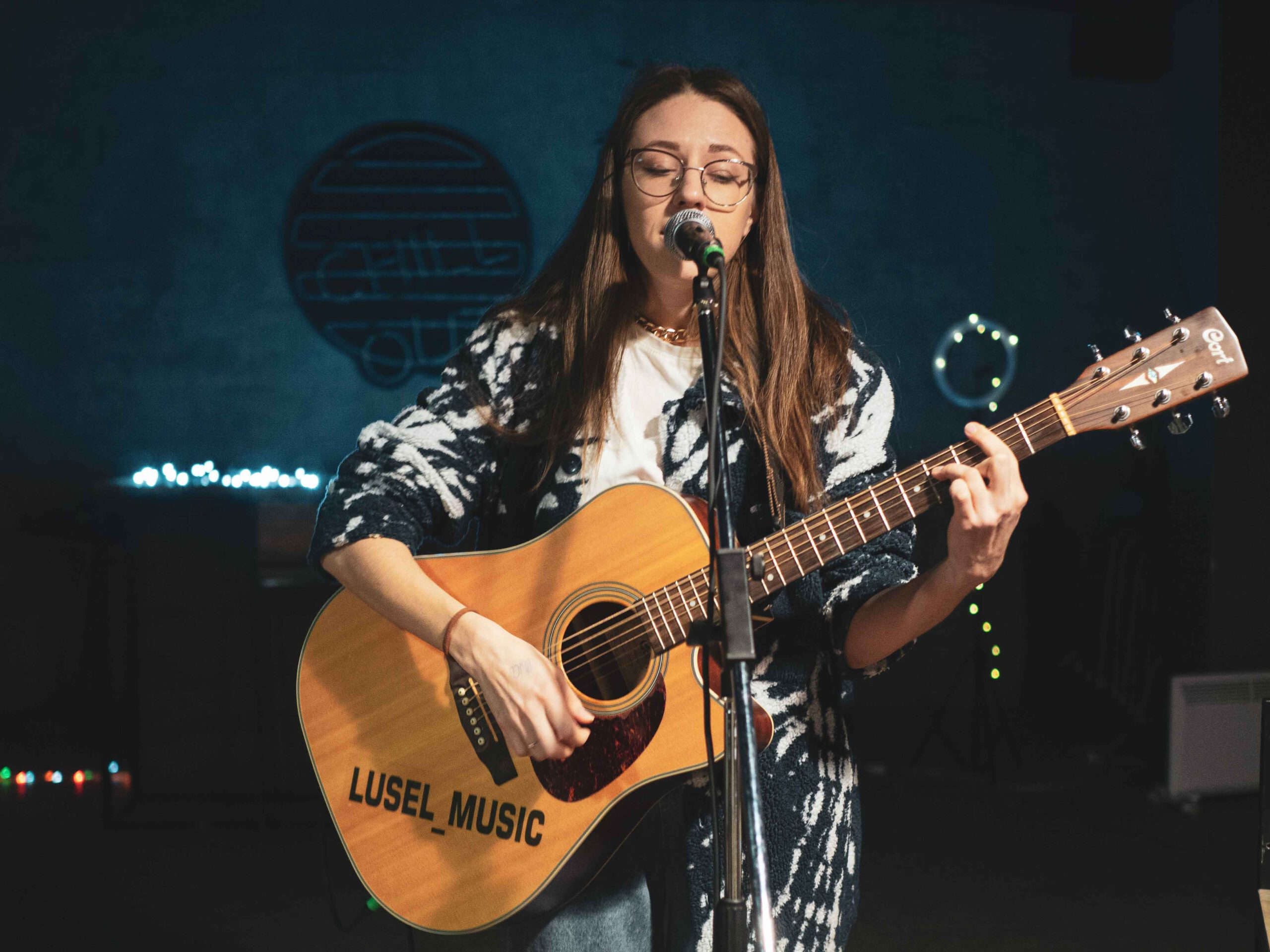 Jugend musiziert wird 60 Jahre alt. Junge Musikerin steht auf Bühne mit Gitarre und singt.