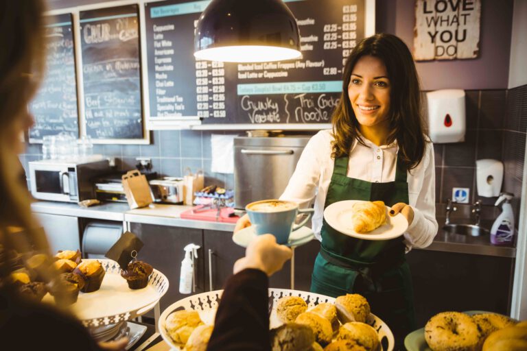 STudentin arbeitet in im Ferienjob als Barista in einem kleinen Café mit anderen Schülern und Studenten.