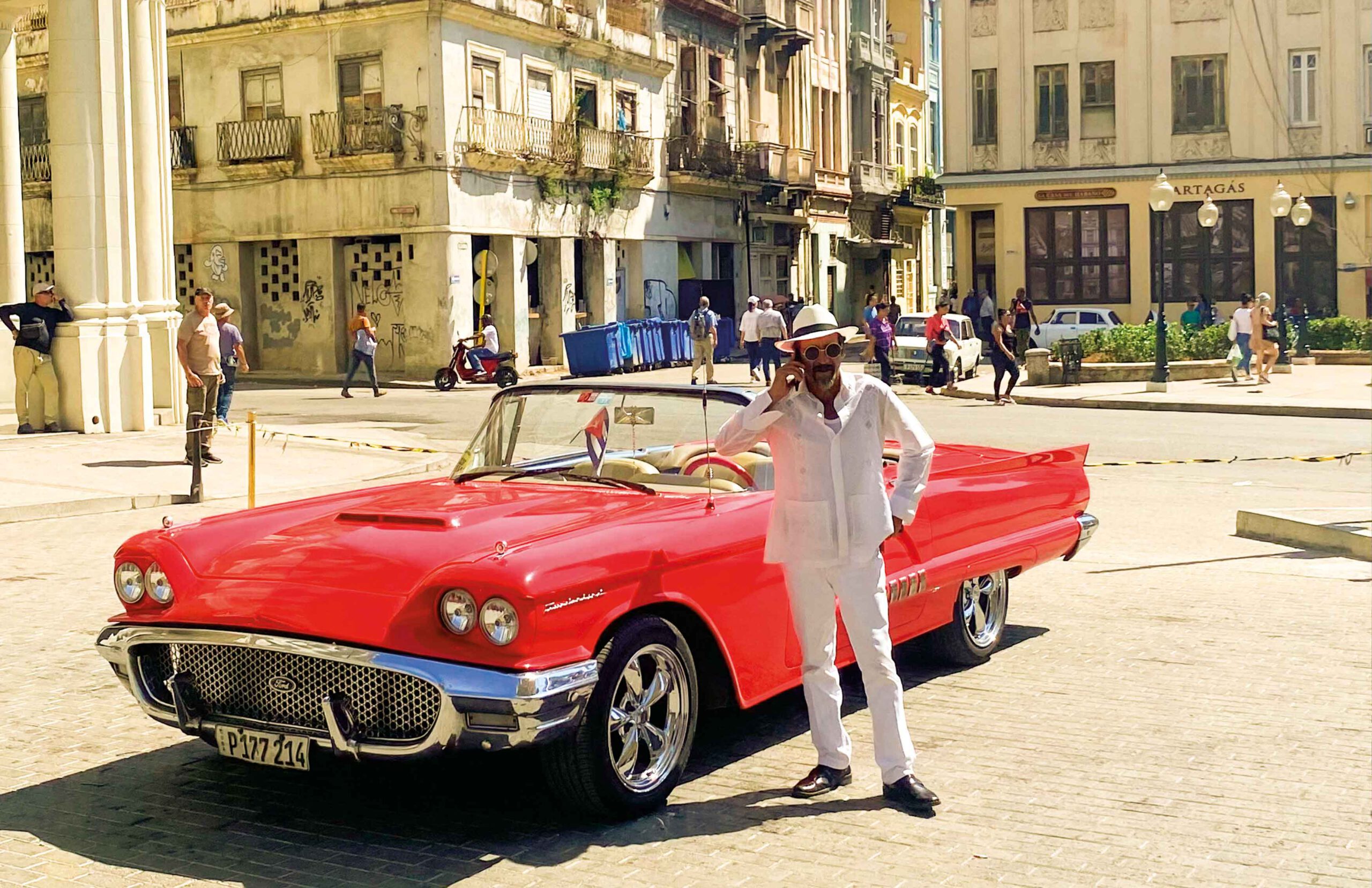 Roter Oldtimer in Old Havana mit telefonierendem Kubaner.