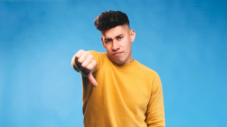 Junger Mann aus der Gen Z zeigt einen Daumen nach unten.