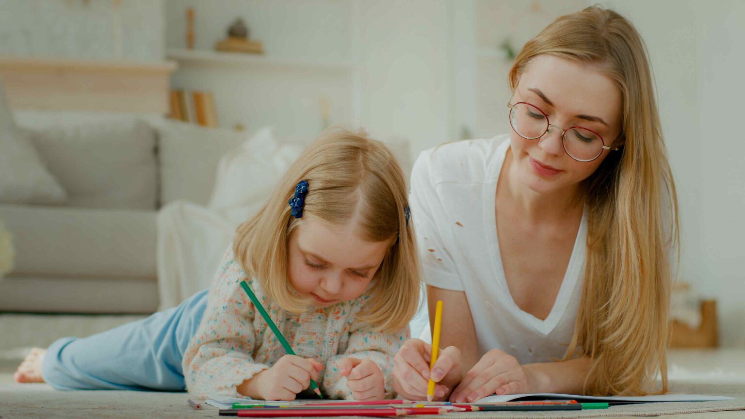 Teenager-Mädchen arbeitet im Nebenjob neben der Schule als Babysitter und malt mit einem Kind.