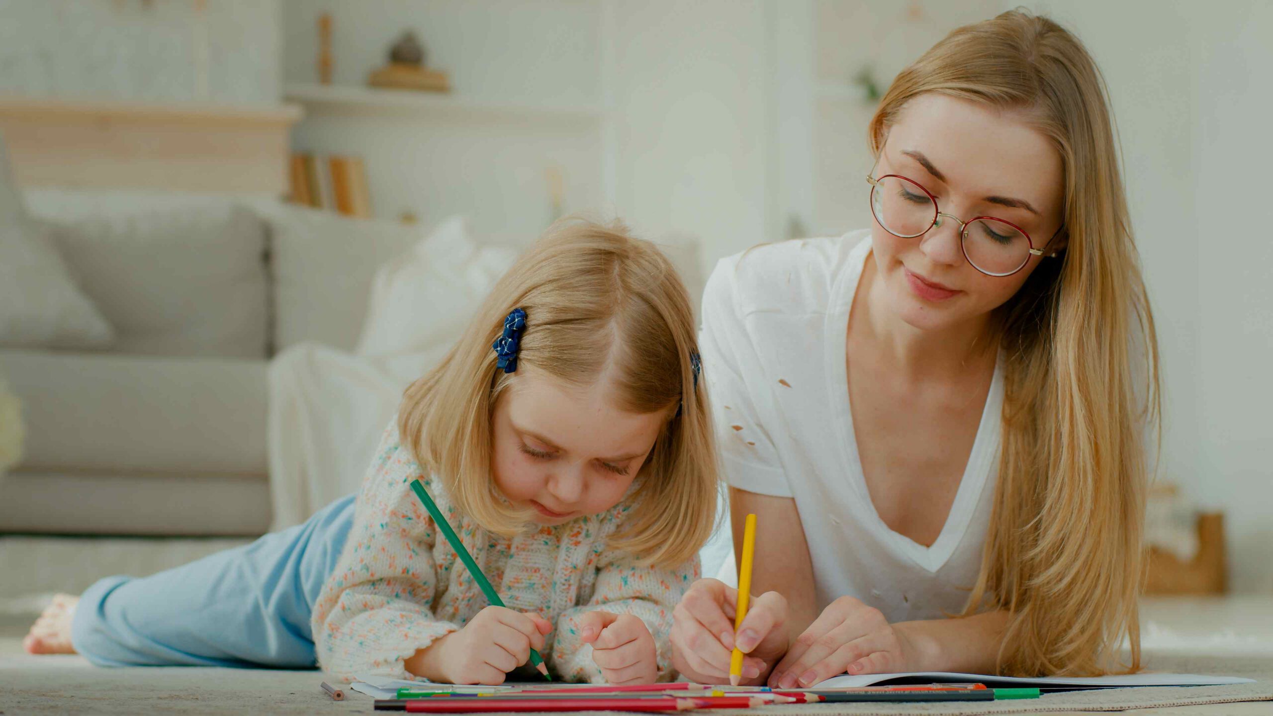 Teenager-Mädchen arbeitet im Nebenjob neben der Schule als Babysitter und malt mit einem Kind.